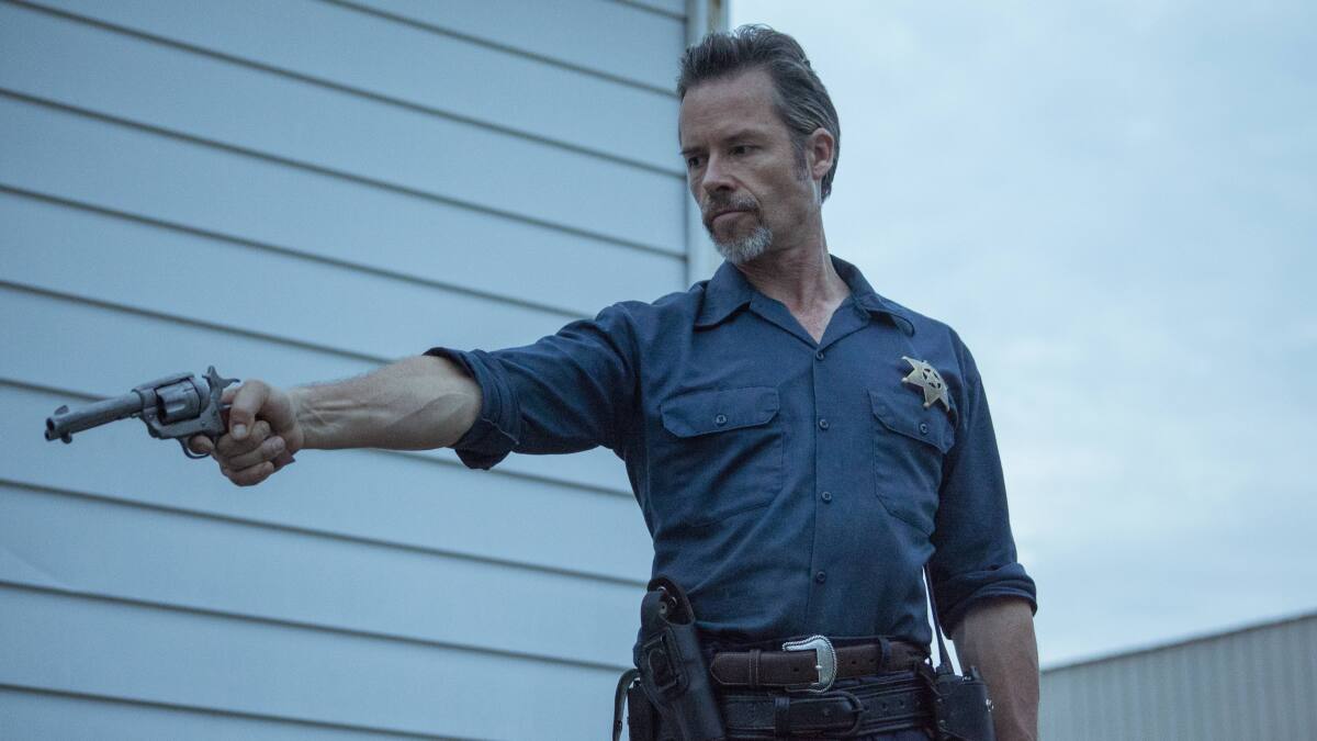 Guy Pearce as a lawman brandishing a gun in the movie “Disturbing the Peace.”