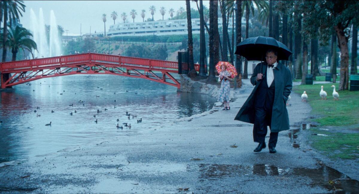Two people walk in the rain under umbrellas.