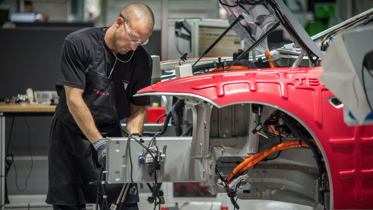 A worker assembles cars on the line at Tesla's factory in Fremont.