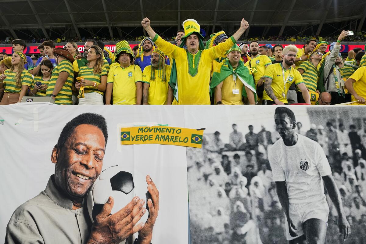 Brazil supporters cheer on the stands above a banner with pictures of soccer legend Pele, while waiting for the start of the World Cup round of 16 soccer match between Brazil and South Korea, at the Education City Stadium in Al Rayyan, Qatar, Monday, Dec. 5, 2022. (AP Photo/Martin Meissner)