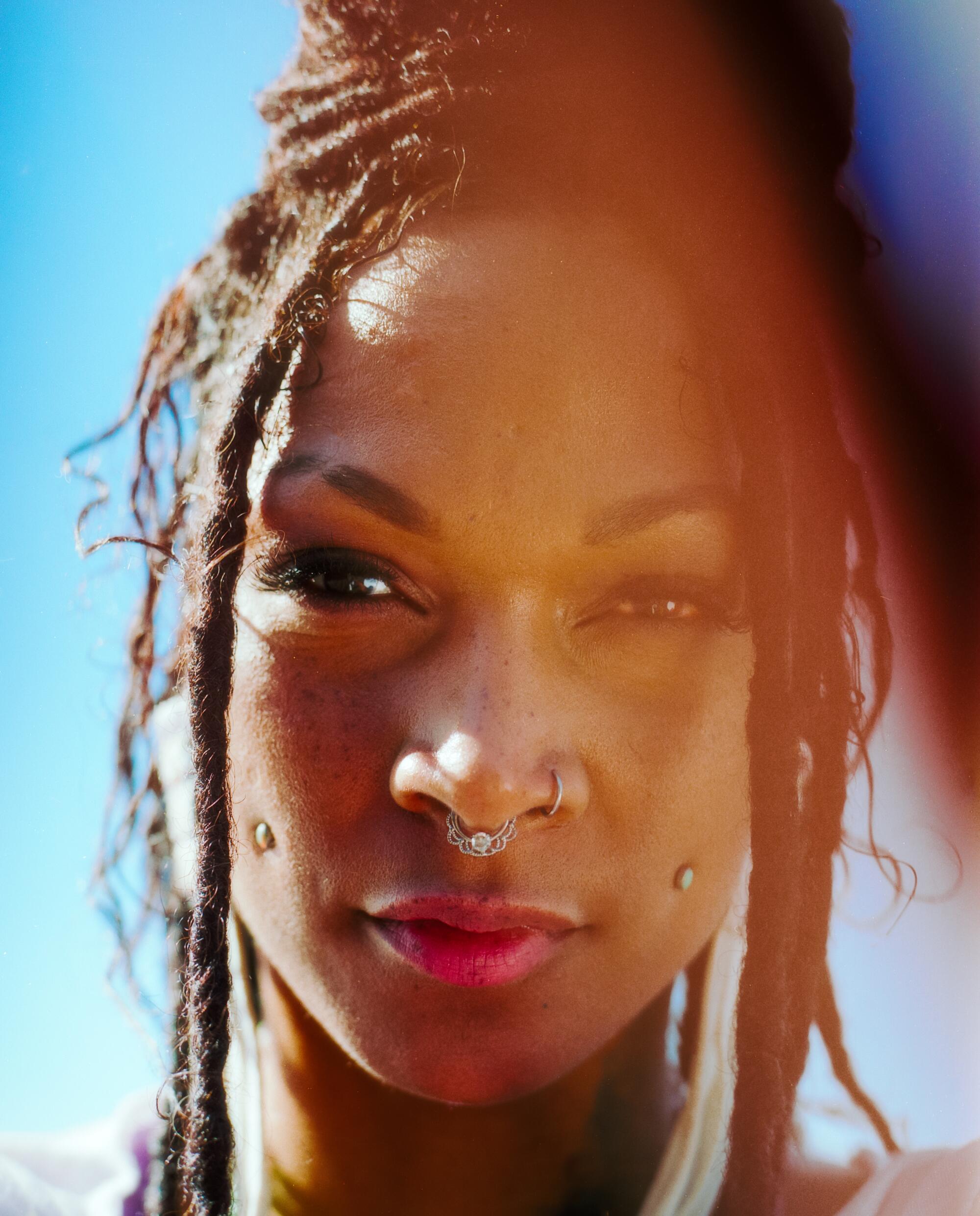 A closeup portrait  of a woman with her hair in thin braids.