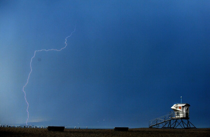 A lightning bolt sears the sky near a lifeguard tower at Bolsa Chica State Beach.