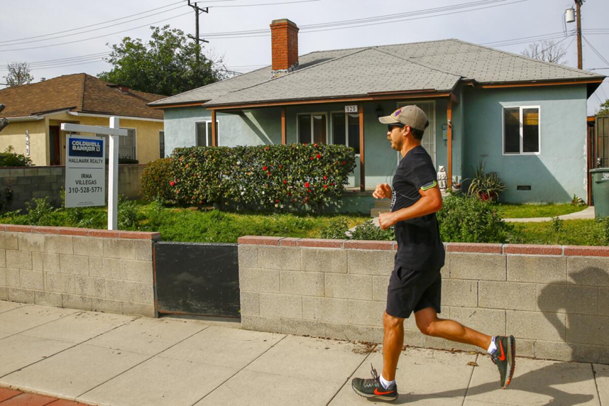 A man jogs past a blue single-family home in Southern California 