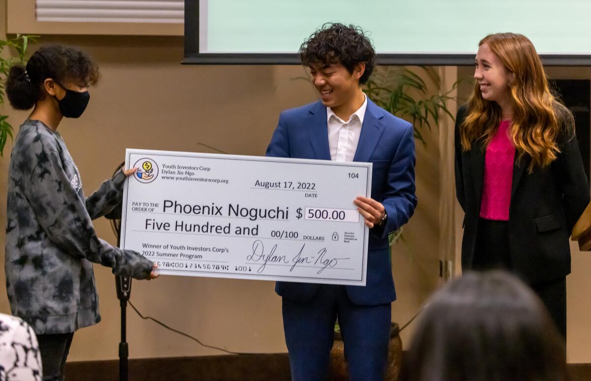 Phoenix Noguchi is presented a grant by Youth Investors Corp. founder Dylan Jin-Ngo and regional director Ella Thimons.