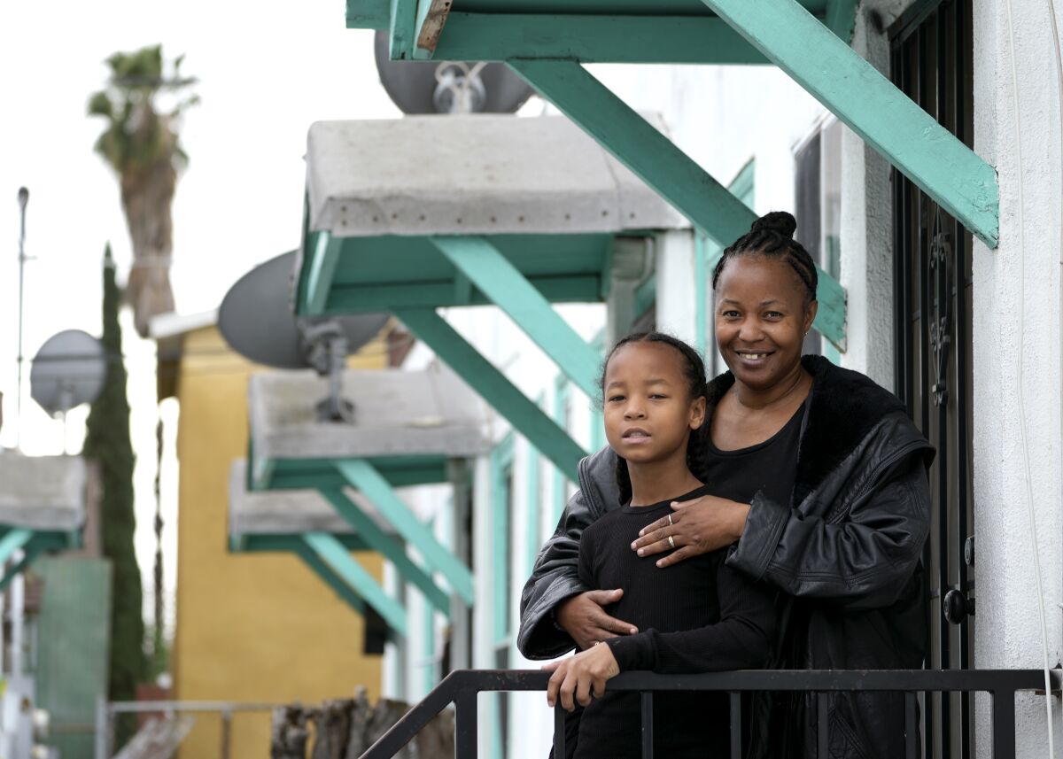 A woman and boy stand at a porch railing