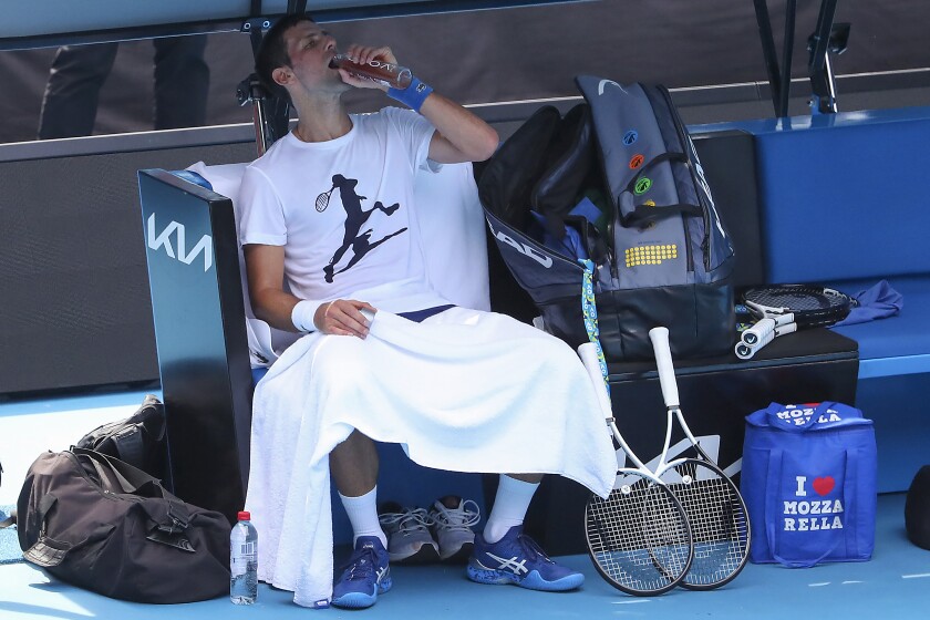 Defending champion Serbia's Novak Djokovic takes a drink during a practice session at the Rod Laver Arena ahead of the Australian Open at Melbourne Park in Melbourne, Australia, Tuesday, Jan. 11, 2022. The prime ministers of Australia and Serbia have discussed Novak Djokovic's precarious visa after the top-ranked Serbian tennis star won a court battle to compete in the Australian Open but still faces the threat of deportation because he is not vaccinated against COVID-19. (Kelly Defina/Pool Photo via AP)