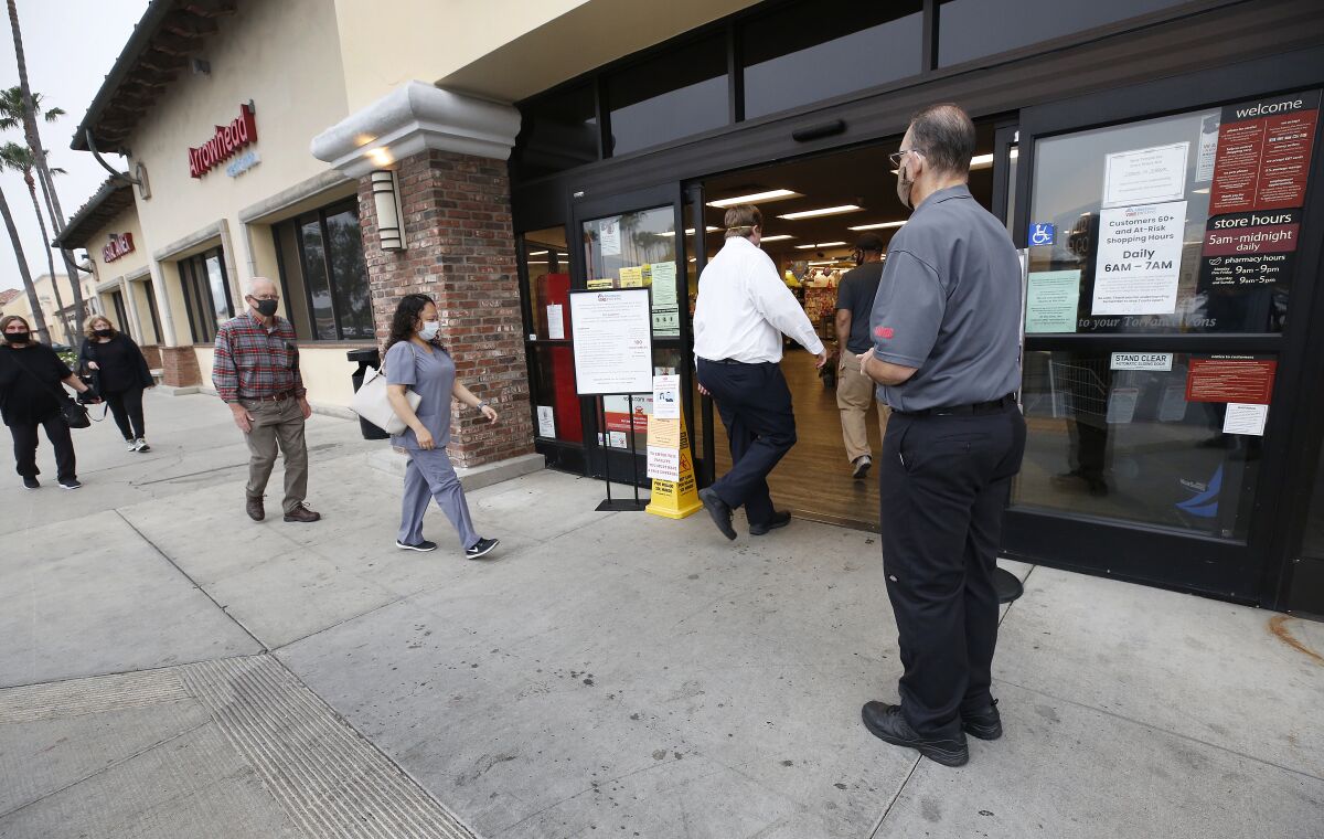 Vons supervisor Anthony Capone, right, greets shoppers in Torrance in April.