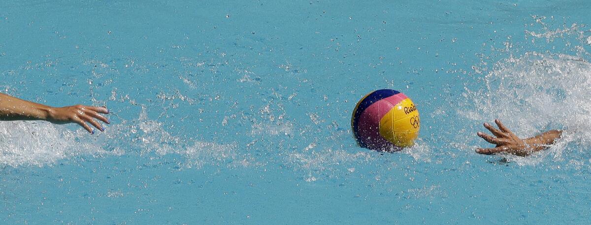 A Spanish and a U.S. player reach for the ball during Tuesday's opening-round women's water polo match.