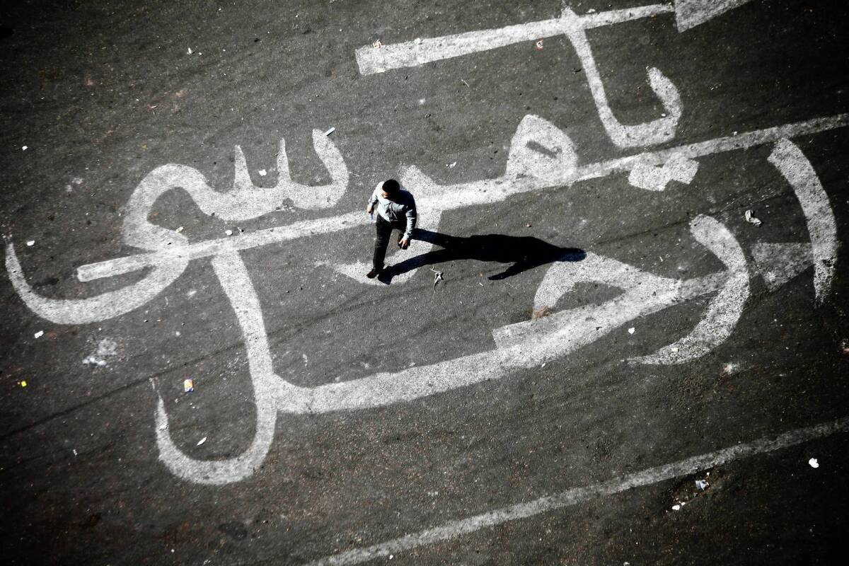 A man walks over graffiti reading "Morsi Go" at Tahrir Square in Cairo on Sunday.
