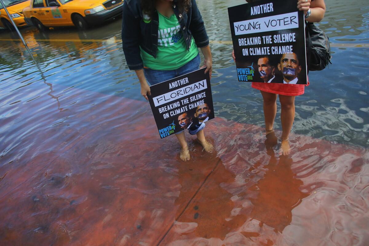 Jacquie Ayala, left, and Amanda Lawrence stand in a flooded street in Miami Beach. After skirting the issue for much of the election, President Obama discussed global warming in his acceptance speech.