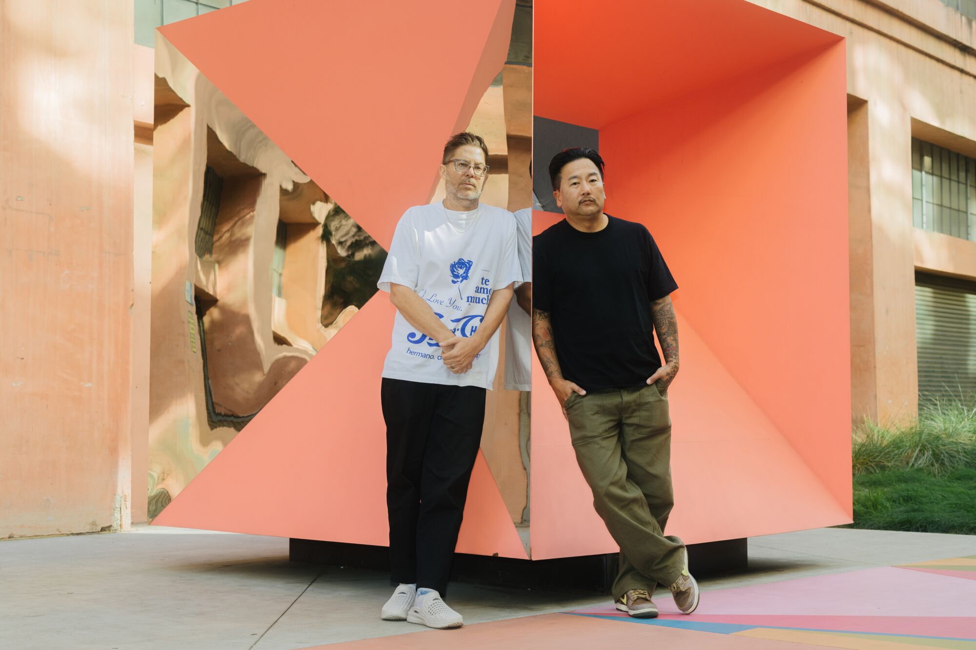 Josh Kun, left, and Roy Choi in front of an orange, square sculpture