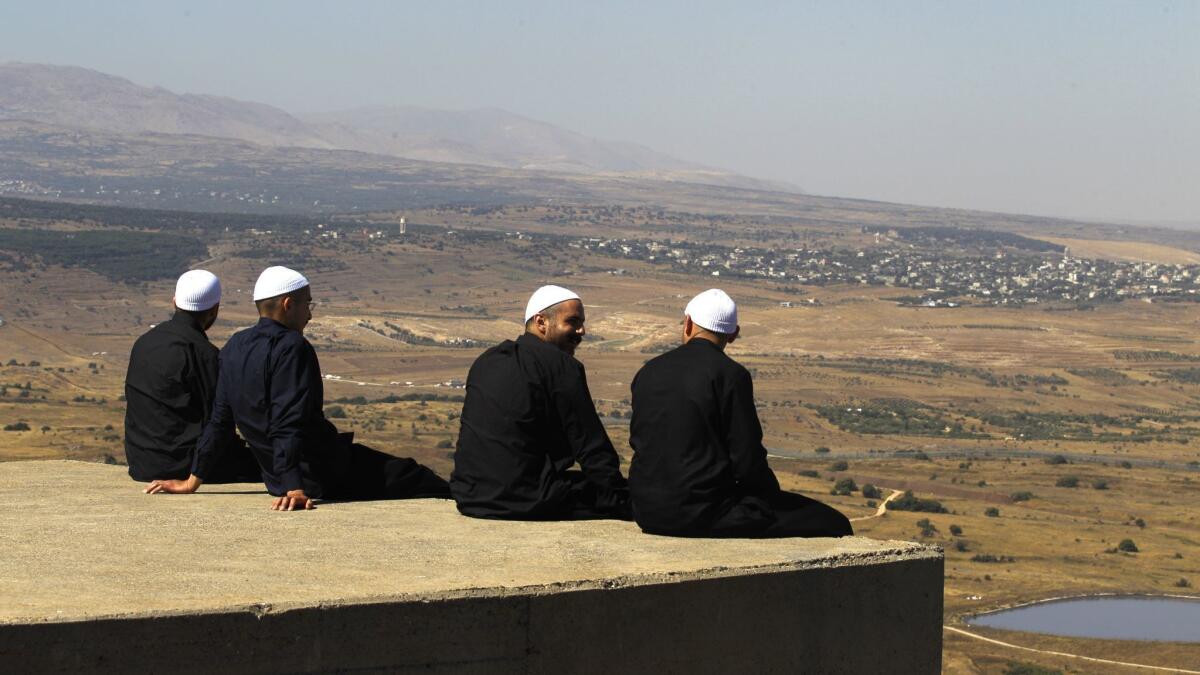 Druze men at the Israeli-annexed Golan Heights look out across the southwestern Syrian province of Quneitra, visible across the border, on July 7, 2018.
