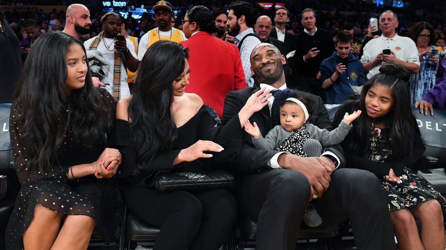 Former Laker Kobe Bryant sits courtside with his family before a jersey retirement ceremony.