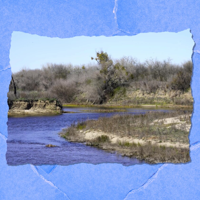 A landscape with brushy hillsides next to a flowing body of water.