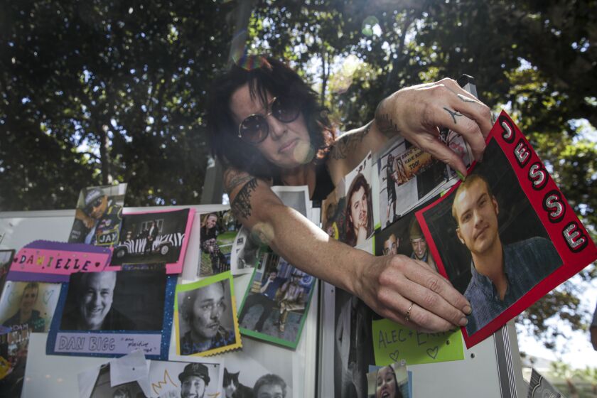 Los Angeles, CA - August 31: Shannon Knox, 38, places the photos overdose victims at a makeshift memorial on International Overdose Awareness Day outside City Hall on Wednesday, Aug. 31, 2022 in Los Angeles, CA. (Irfan Khan / Los Angeles Times)