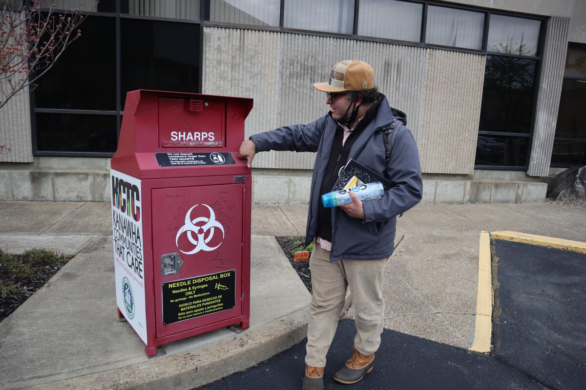 Joe Solomon, Democratic candidate for city council and co-director of the non-profit Solutions Oriented Addiction Response, stops by a syringe disposal box outside the Kanawha-Charleston Health Department, Tuesday, April 5, 2022, in Charleston, W.Va. Solomon had spent three days eating at soup kitchens and sleeping under bridges and in parking lots while interviewing residents about the changes they’d like to see in the city’s response to issues like homelessness and substance use. (AP Photo/Leah Willingham)