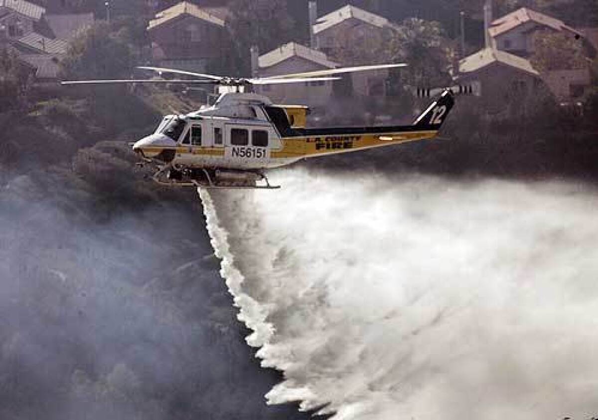 A helicopter drops water on a blaze in the north end of Saugus in the Santa Clarita Valley.