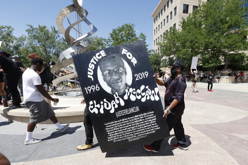 FILE - In this June 27, 2020, file photo, demonstrators carry a giant placard during a rally and march over the death of Elijah McClain outside the police department in Aurora, Colo. Colorado’s attorney general plans to make an announcement Wednesday, Sept. 1, 2021 about the grand jury investigation into the death of McClain, a Black man who was put in a chokehold and injected with a powerful sedative two years ago in suburban Denver. (AP Photo/David Zalubowski, File)