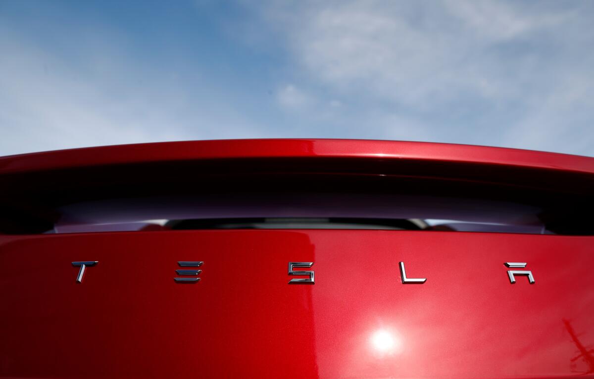 A company's name on a red car reads Tesla.