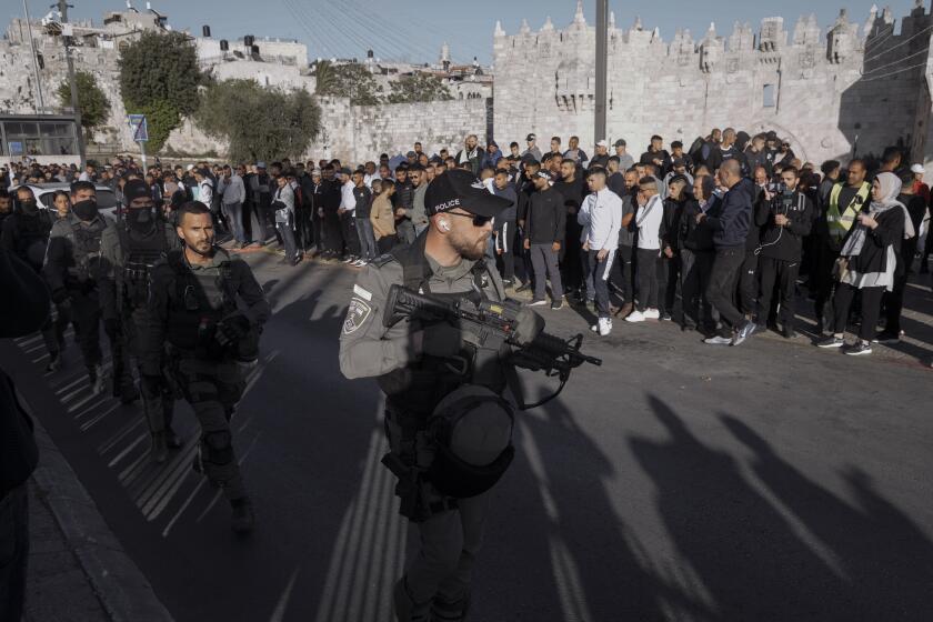 Palestinians looks on as Israeli security forces patrol near Damascus Gate, just outside Jerusalem's Old City, Wednesday, April 20, 2022. Police prevented hundreds of ultra-nationalist Israelis from marching around predominantly Palestinian areas of Jerusalem's Old City. The event planned for Wednesday was similar to one that served as one of the triggers of last year's Israel-Gaza war. (AP Photo/Mahmoud Illean)