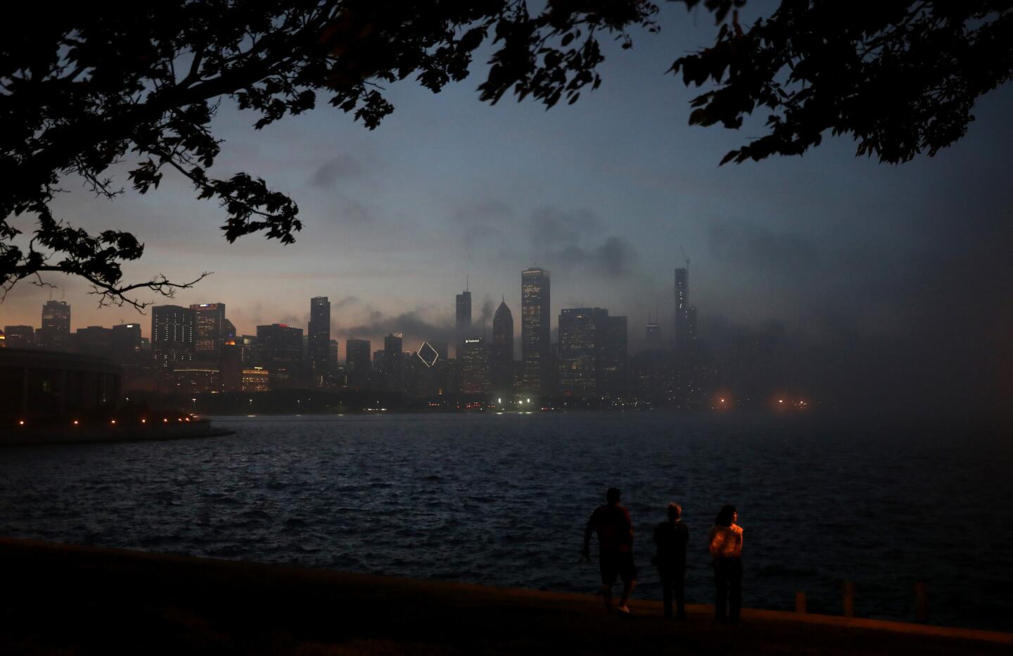 Three people take in the scene as heavy fog rolls into downtown Chicago on June 5, 2019.