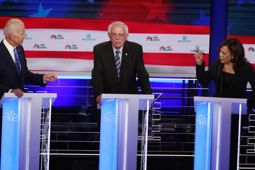 Democratic presidential candidate former Vice-President Joe Biden, left, and Sen. Kamala Harris, D-Calif., spar during the Democratic primary debate hosted by NBC News at the Adrienne Arsht Center for the Performing Arts, Thursday, June 27, 2019, in Miami. Sen. Bernie Sanders, I-Vt., is in the center. (AP Photo/Wilfredo Lee)