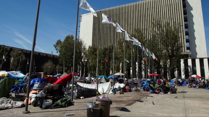 Homeless individuals gather at an encampment at the Santa Ana Civic Center near the Orange County Courthouse.