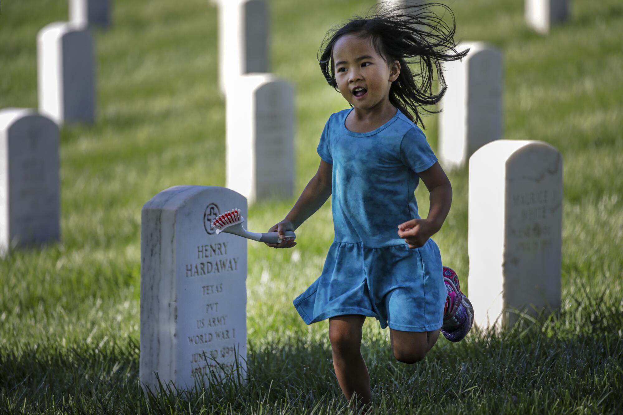 Emma Chan, 3, daughter of a UCLA alumni, rushes to clean a headstone