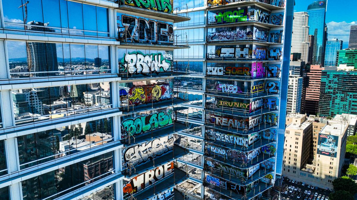 Graffiti covers multiple floors of a skyscraper with a mirrored glass facade