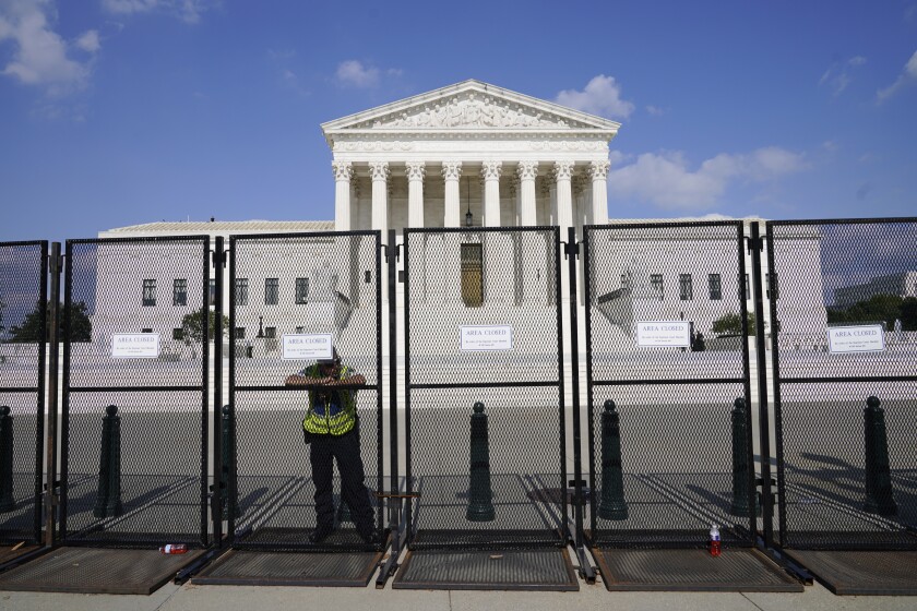 An officer rests on a fence outside the Supreme Court in Washington, Friday, June 24, 2022. The Supreme Court has ended constitutional protections for abortion that had been in place nearly 50 years, a decision by its conservative majority to overturn the court's landmark abortion cases. (AP Photo/Jacquelyn Martin)