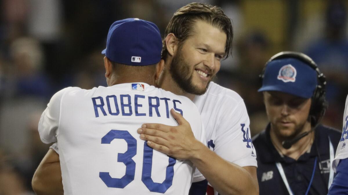 Clayton Kershaw embraces Dodgers manager Dave Roberts as the team celebrates a 3-0 victory over the Braves in Game 2 of the National League Divisional Series at Dodger Stadium.