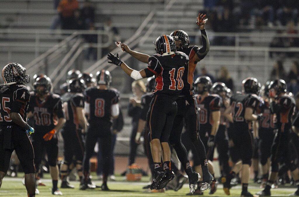 Huntington Beach's Kai Ross, right, celebrates with Brayden McRae after he picked off a tipped pass during a game against Newport Harbor on Friday.