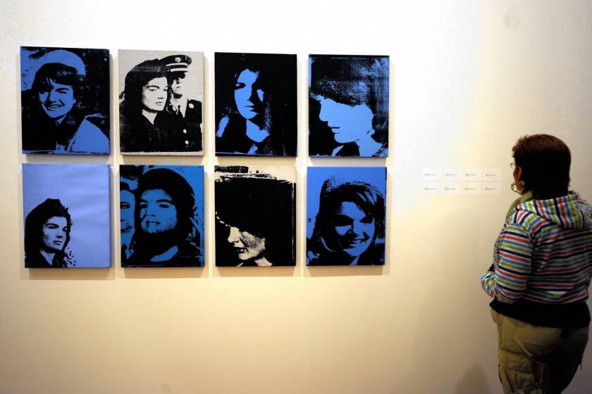 A visitor looks at paintings of former First Lady Jacqueline Lee Bouvier Kennedy Onassis, from Andy Warhol's series "Jackie, 1964" in Bogota. )