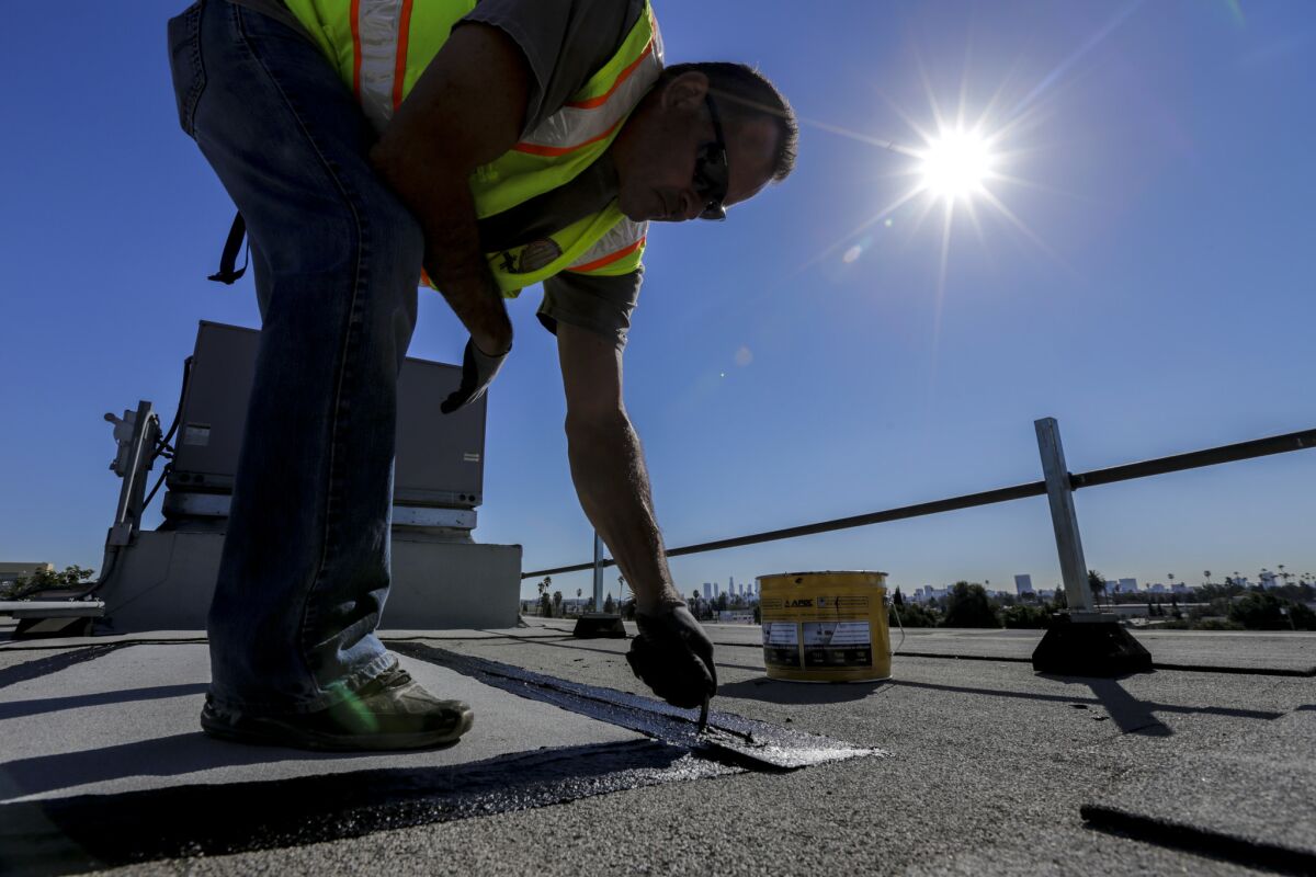 Rick Rodriguez, a roofer for Los Angeles Unified School District, fixes a rain-related leak on the roof of Le Conte Middle School's auditorium on Wednesday, Feb. 3.