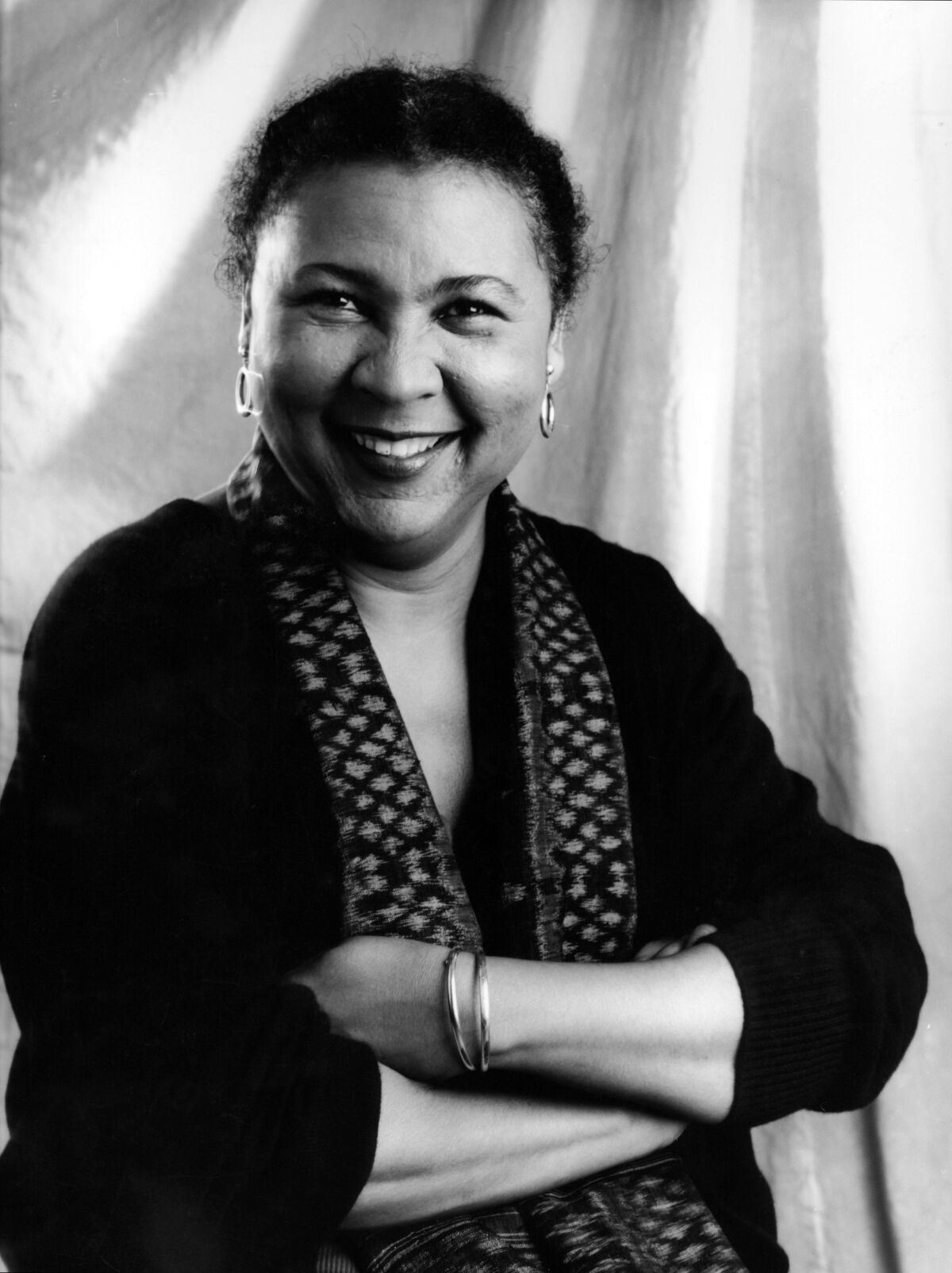 bell hooks (born Gloria Jean Watkins) smiling with her arms crossed