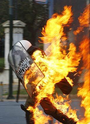 A policeman is covered in flames from a petrol bomb thrown by rioters during clashes in central Athens. Throughout Greece, youths and authorities have clashed for days in protests sparked by the fatal police shooting of a teenager.