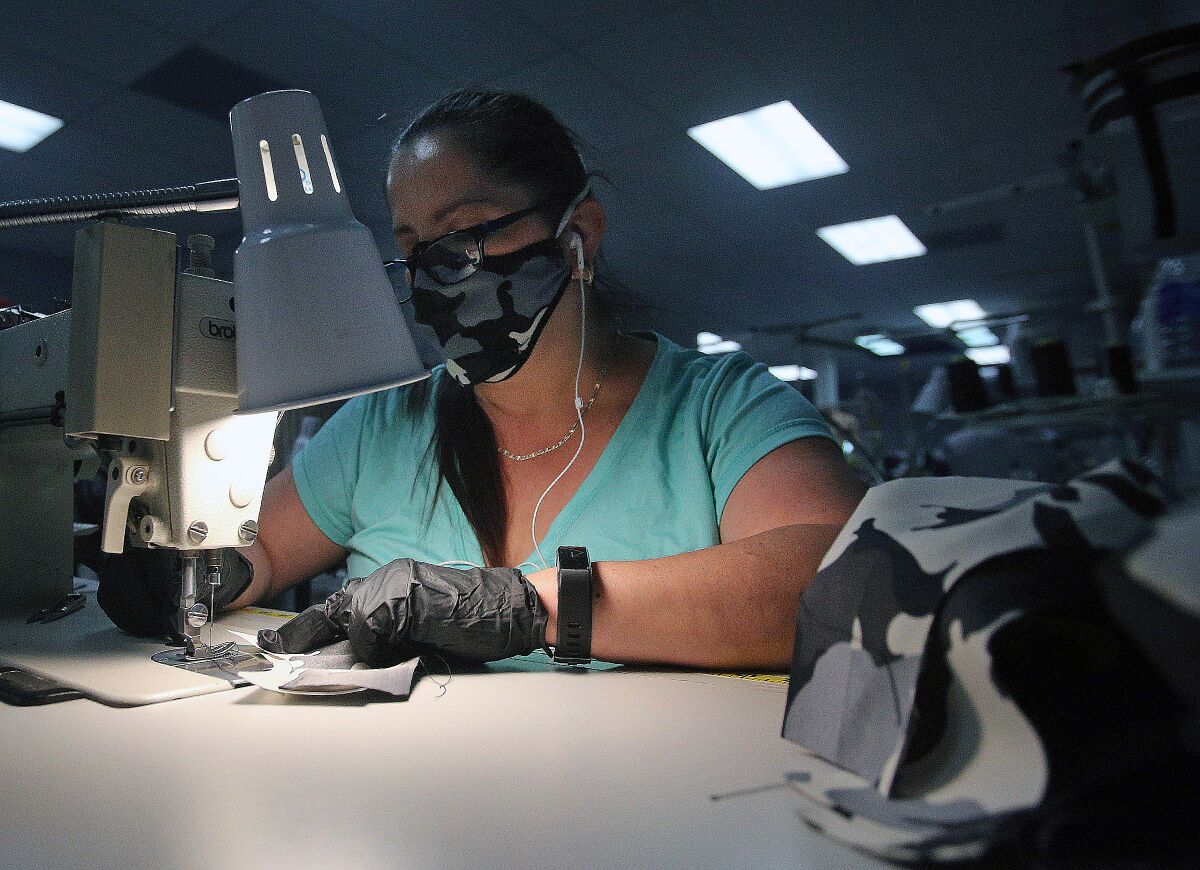 Mia Calderon, of Los Angeles, on the first day of production, sews protective masks at LiquidSky Sports in Burbank on Tuesday.