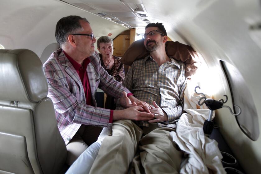 In this July 11, 2013 file photo, Jim Obergefell, left and John Arthur, right, are married by officiant Paulette Roberts, rear center, in a plane on the tarmac at Baltimore/Washington International Airport in Glen Burnie, Md. Federal Judge Timothy Black on Wednesday, Dec. 18, 2013, questioned the constitutionality of Ohio's ban on gay marriage and whether state officials have the authority to refuse to recognize the marriages of gay couples who wed in other states. Black earlier ruled in favor of the couple in a lawsuit seeking to recognize the couples' marriage on Arthur’s death certificate before he died in October from ALS. (AP Photo/The Cincinnati Enquirer, Glenn Hartong, File) MANDATORY CREDIT, NO SALES