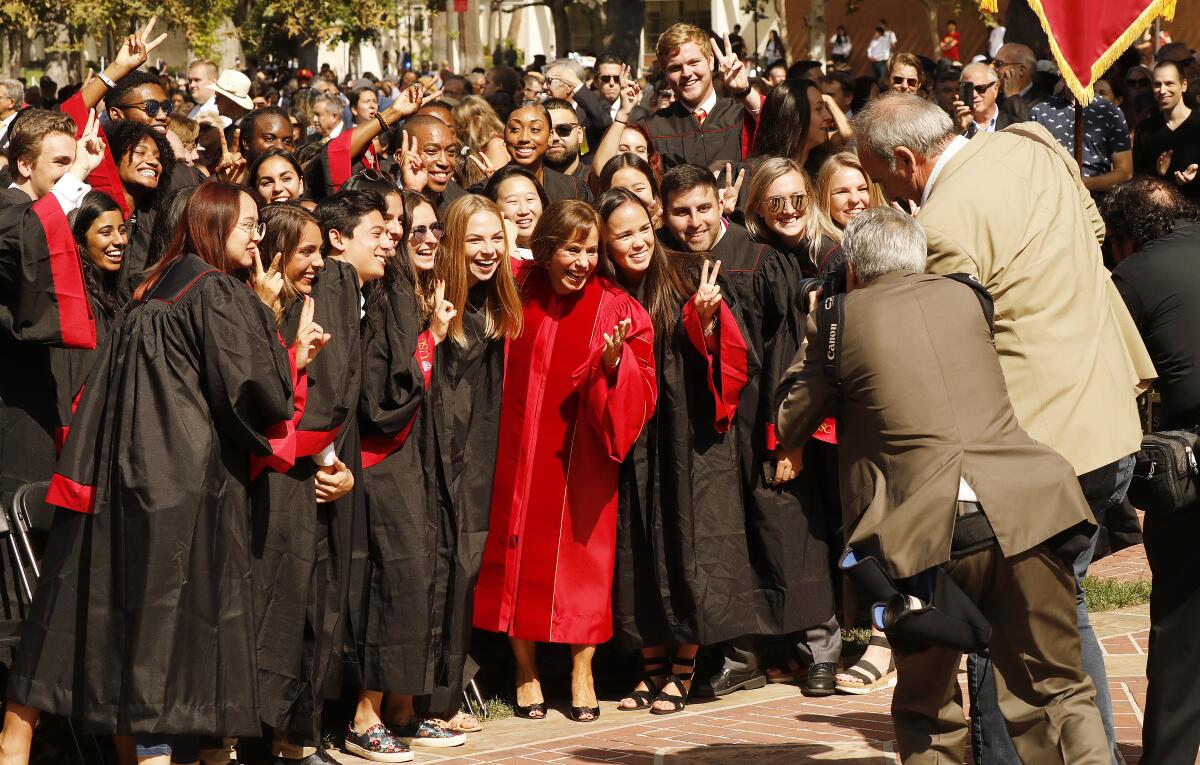 Dr. Carol L. Folt, center, runs to pose with USC students for university photographers during Folt’s inauguration as USC’s 12th president.