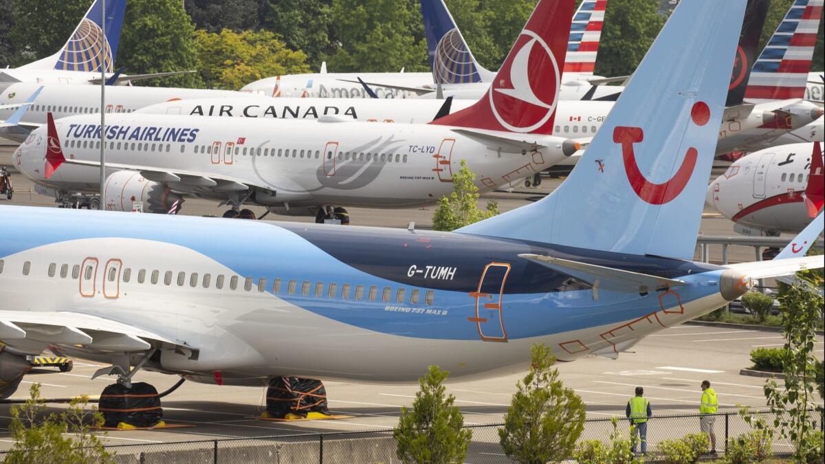 Workers stand near Boeing 737 Max airplanes as they sit parked at a Boeing facility adjacent to King County International Airport, known as Boeing Field, in Seattle in May.