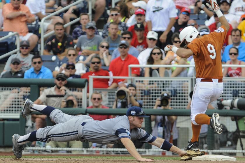 UC Irvine first baseman Connor Spencer, left, leaps to first base as Texas' C.J Hinojosa runs during their College World Series game on Saturday.