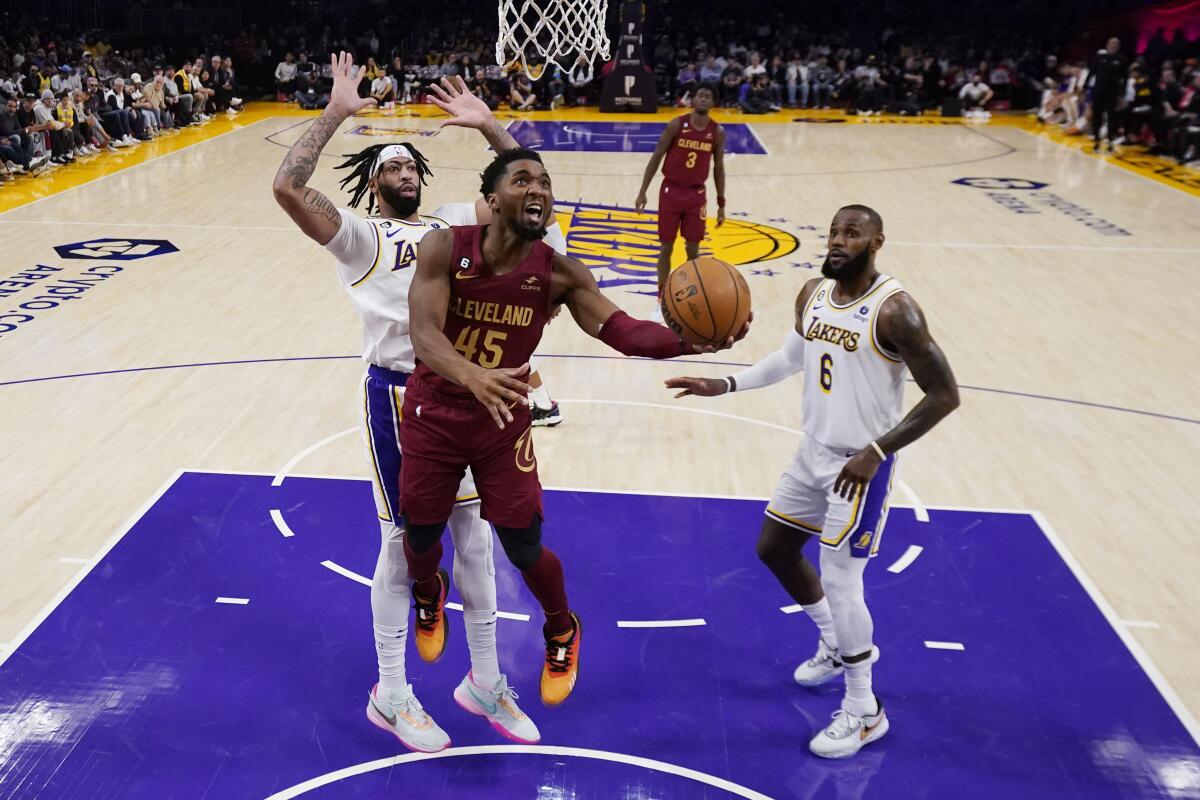 Cleveland Cavaliers guard Donovan Mitchell (45) drives past Los Angeles Lakers forward Anthony Davis, left, and forward LeBron James during the first half of an NBA basketball game Sunday, Nov. 6, 2022, in Los Angeles. (AP Photo/Marcio Jose Sanchez)