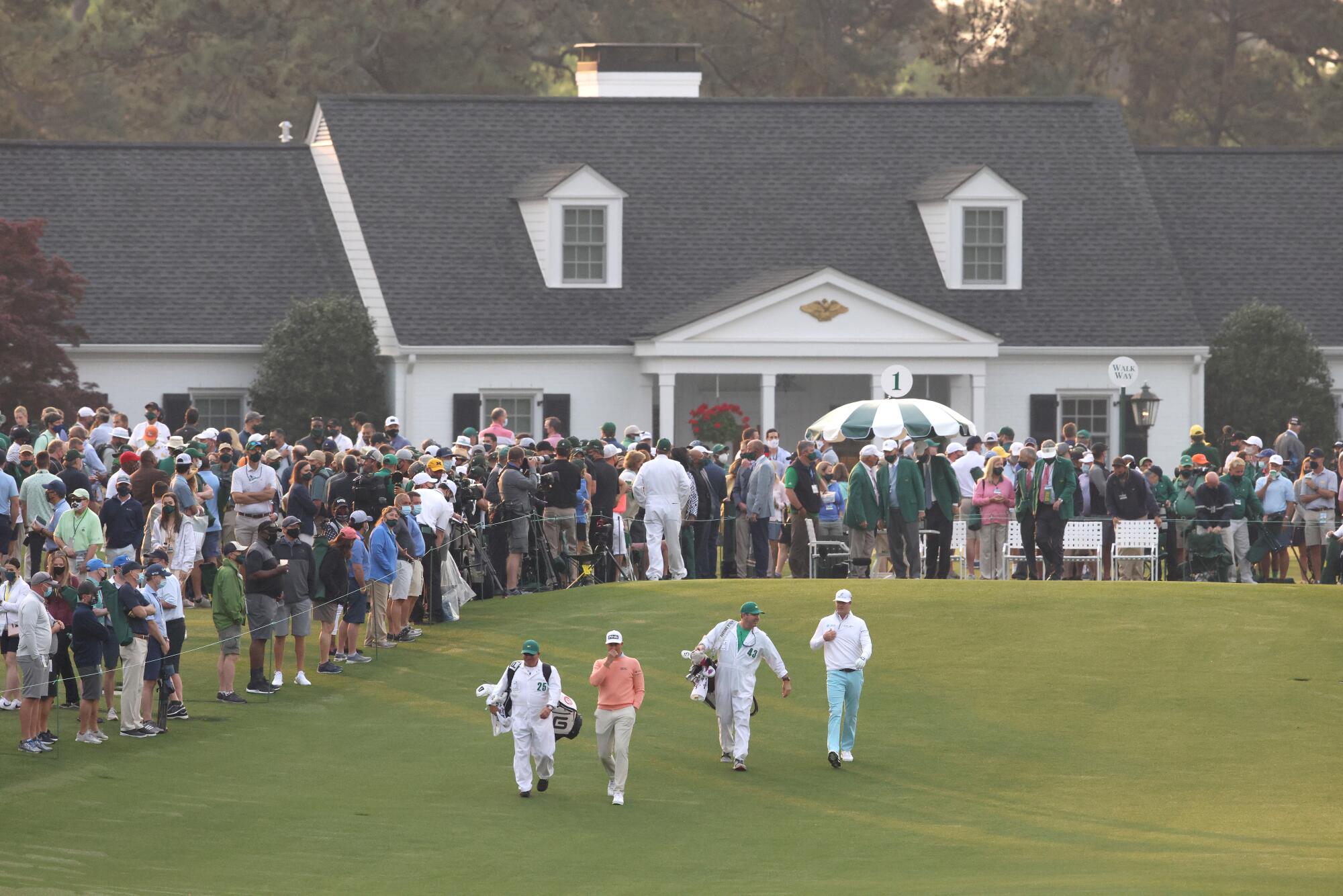 Golfers walk from the tee area after starting their round