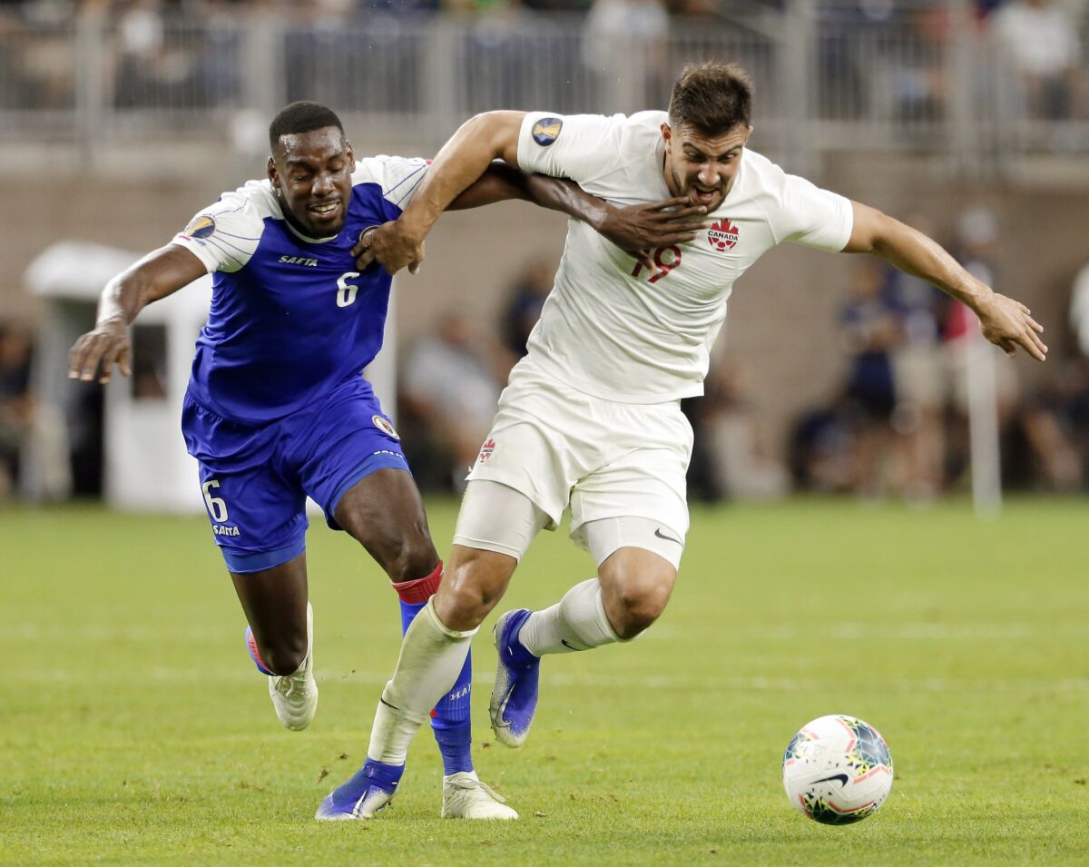 Haiti defender Jems Geffrard (6) and Canada forward Lucas Cavallini (19) pull on each other as they chase the ball during the second half of a CONCACAF Gold Cup soccer quarterfinal on Saturday in Houston.