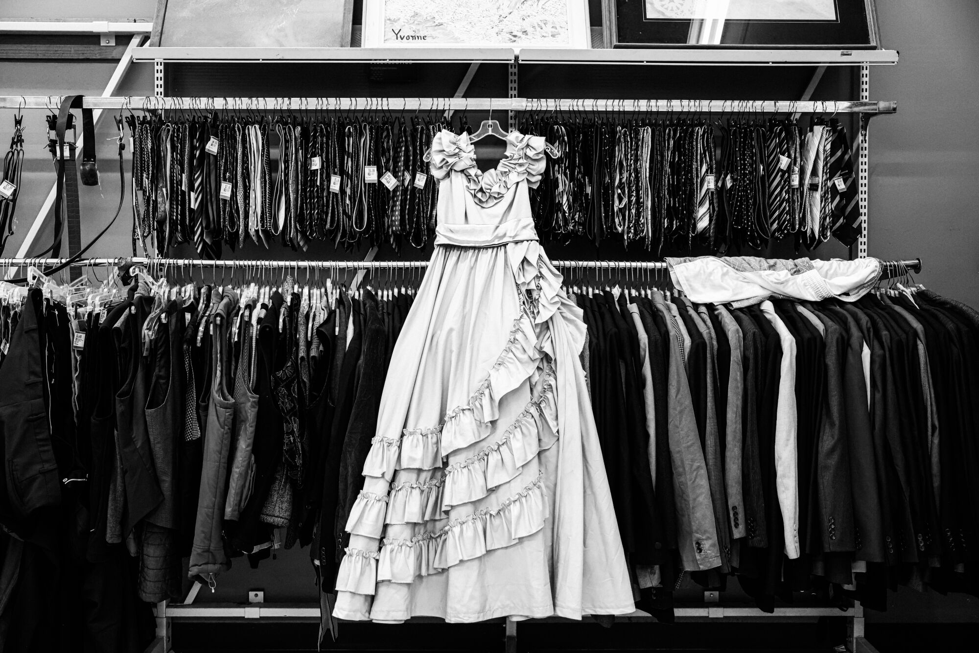 a black-and-white photo of a gown hanging on a clothing rack 