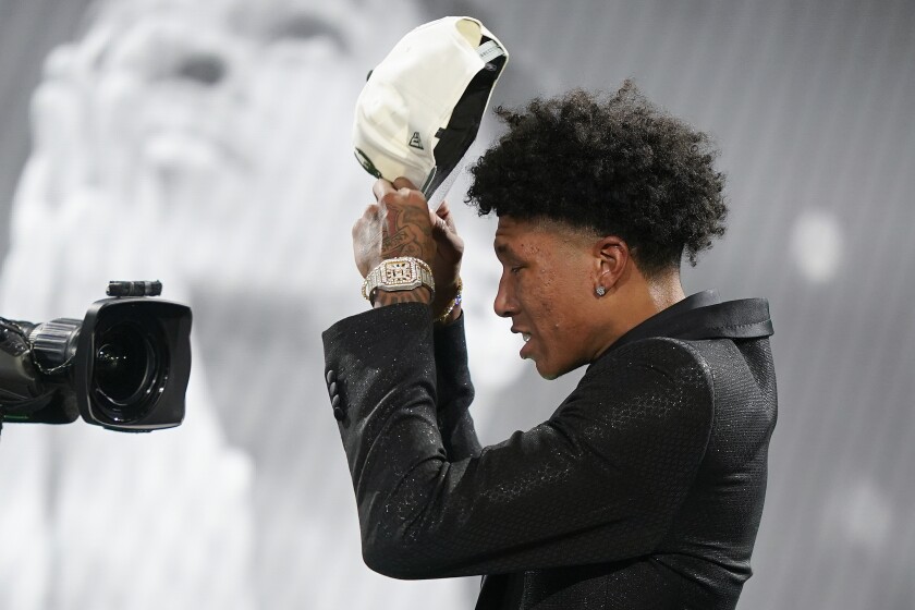 MarJon Beauchamp dons a Milwaukee Bucks cap after being selected 24th overall by the Bucks in the NBA basketball draft, Thursday, June 23, 2022, in New York. (AP Photo/John Minchillo)