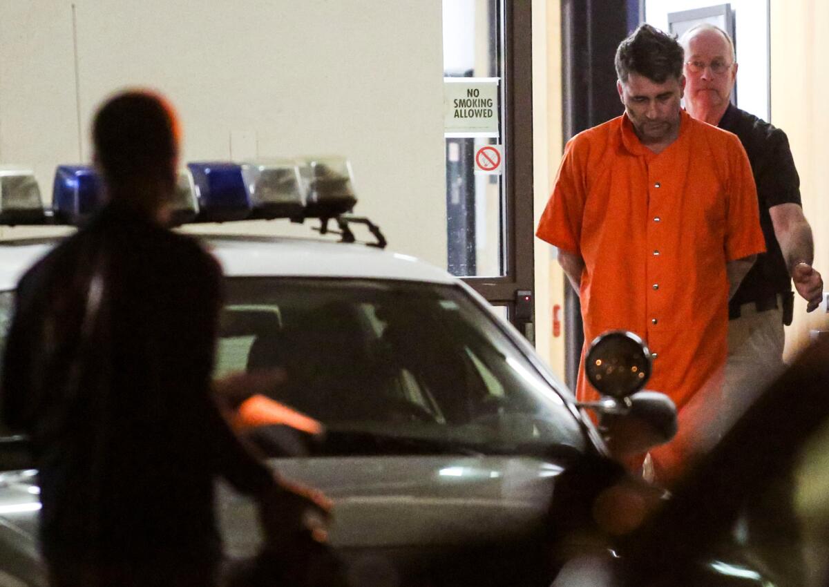 Gary Lee Bullock is led by law enforcement officers into a car in Eureka on Jan. 2 after his arrest in the killing of a respected priest and educator.