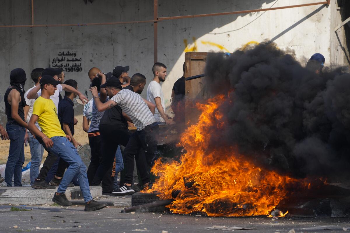 Demonstrators clash with soldiers next to a fire in the street in the West Bank.