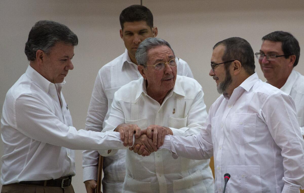 Cuban President Raul Castro, center, encourages Colombian President Juan Manuel Santos, left, and Timoleon Jimenez, commander of the Revolutionary Armed Forces of Colombia, to shake hands in Havana.