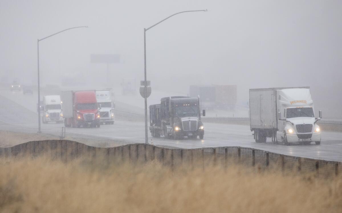 Trucks drive through blowing snow on the 5 Freeway in Gorman on Wednesday morning.